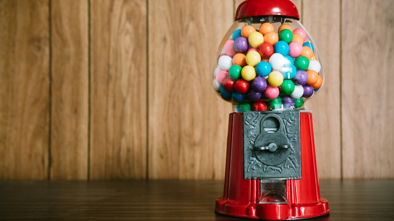 A Classic Red gumball machine filled with colorful gumballs