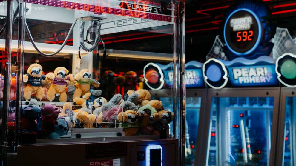 Crane game arcade machine filled with plush prizes