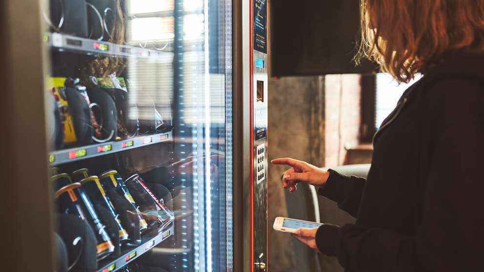 Person using a vending machine with snacks and drinks